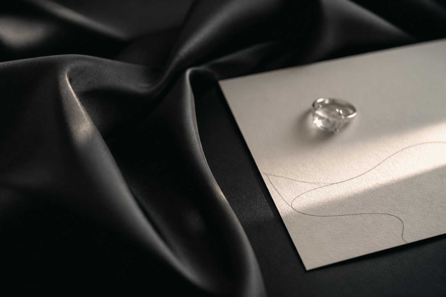 Editorial still life with a generic ring impression on black fabric and an ivory note