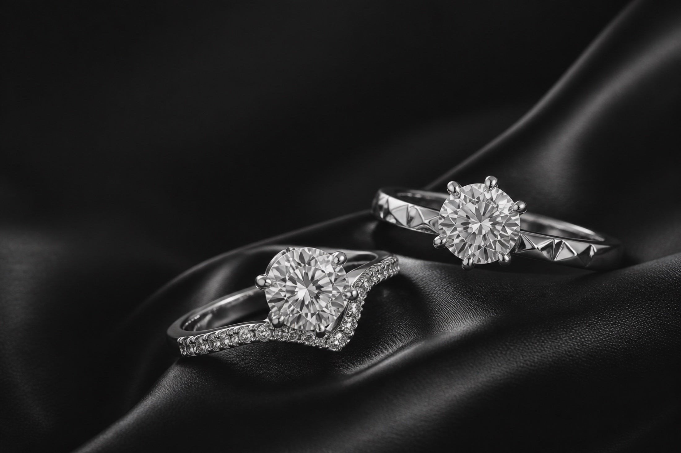 Two clear-stone ring forms on dark satin in an editorial still life